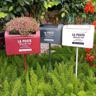 Wrought iron metal garden planter mailbox stands with pink flowers outdoors