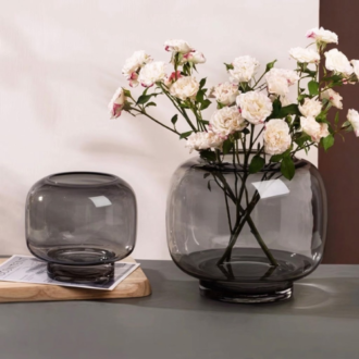 Tinted smoky round glassware for growing plants displaying floral stems on a tabletop