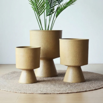 Set of three elevated beige pedestal planters featuring a smooth geometric base, ideal for indoor styling and garden patios.
